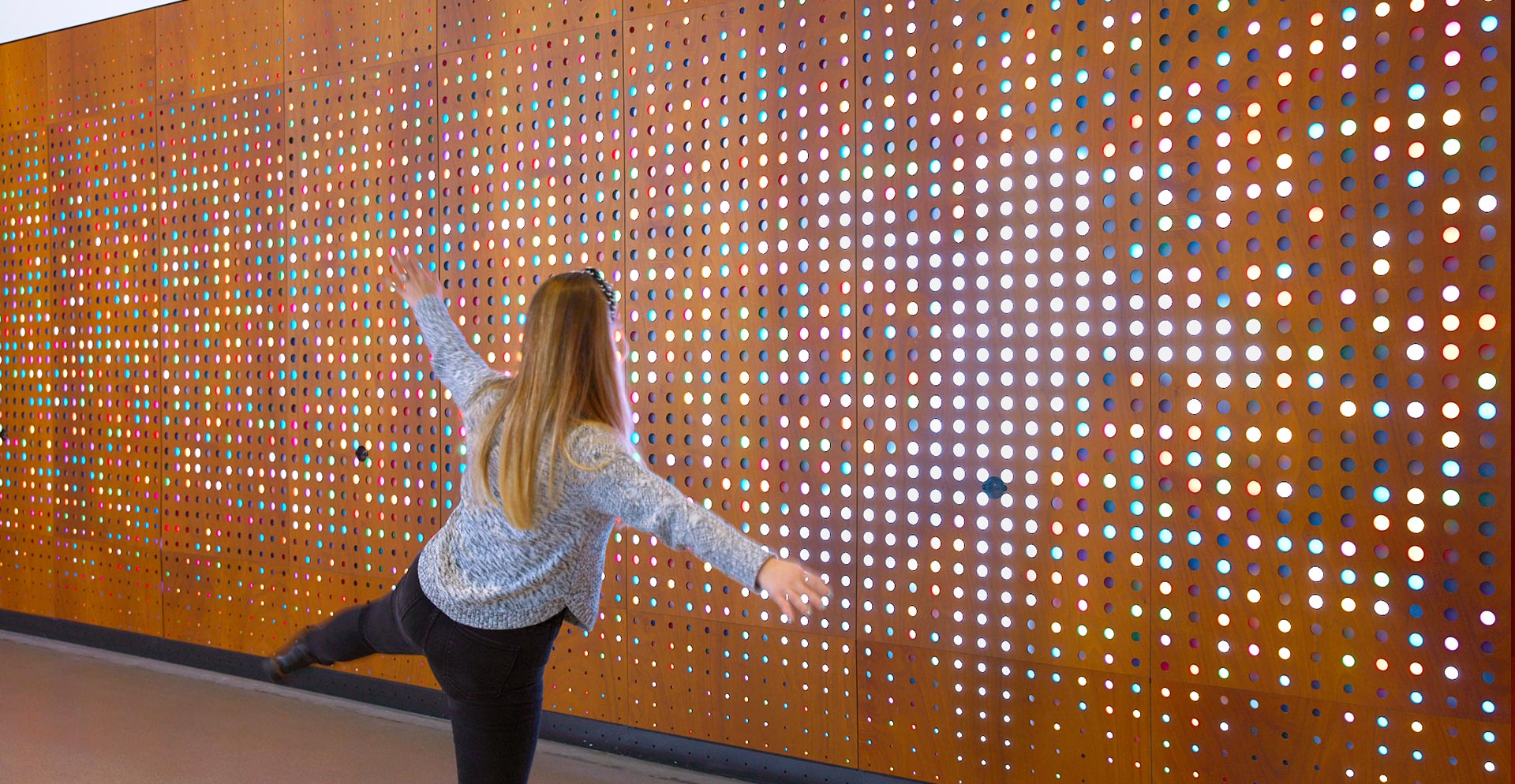 A person standing in front of a wall with lights.