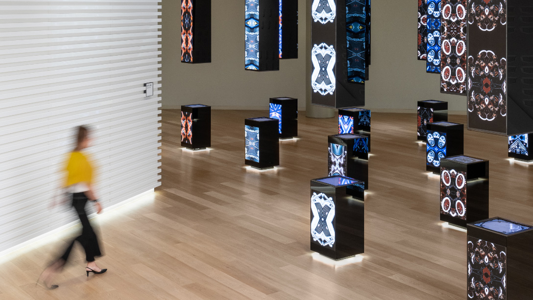 A person walking in a room with many speakers.
