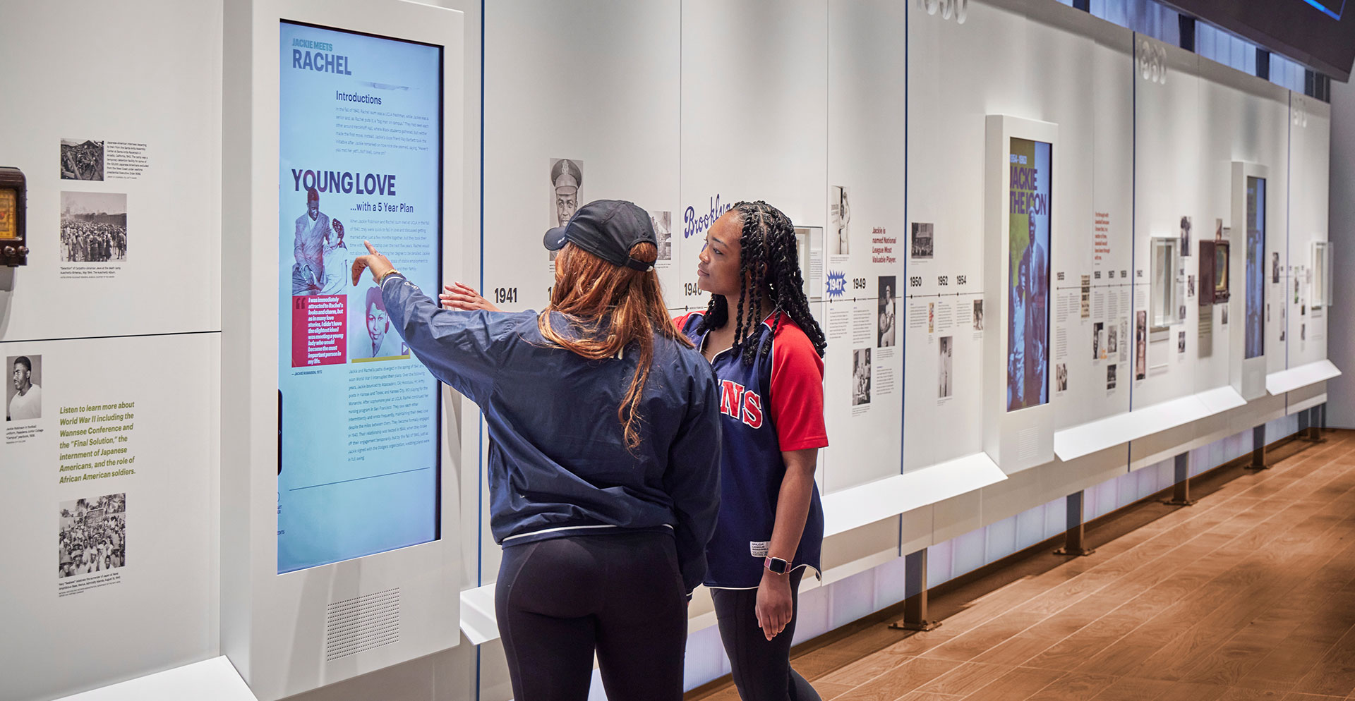 A couple of women looking at a poster on a wall.