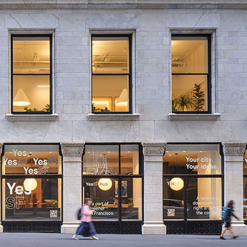 A building with windows and people walking by.