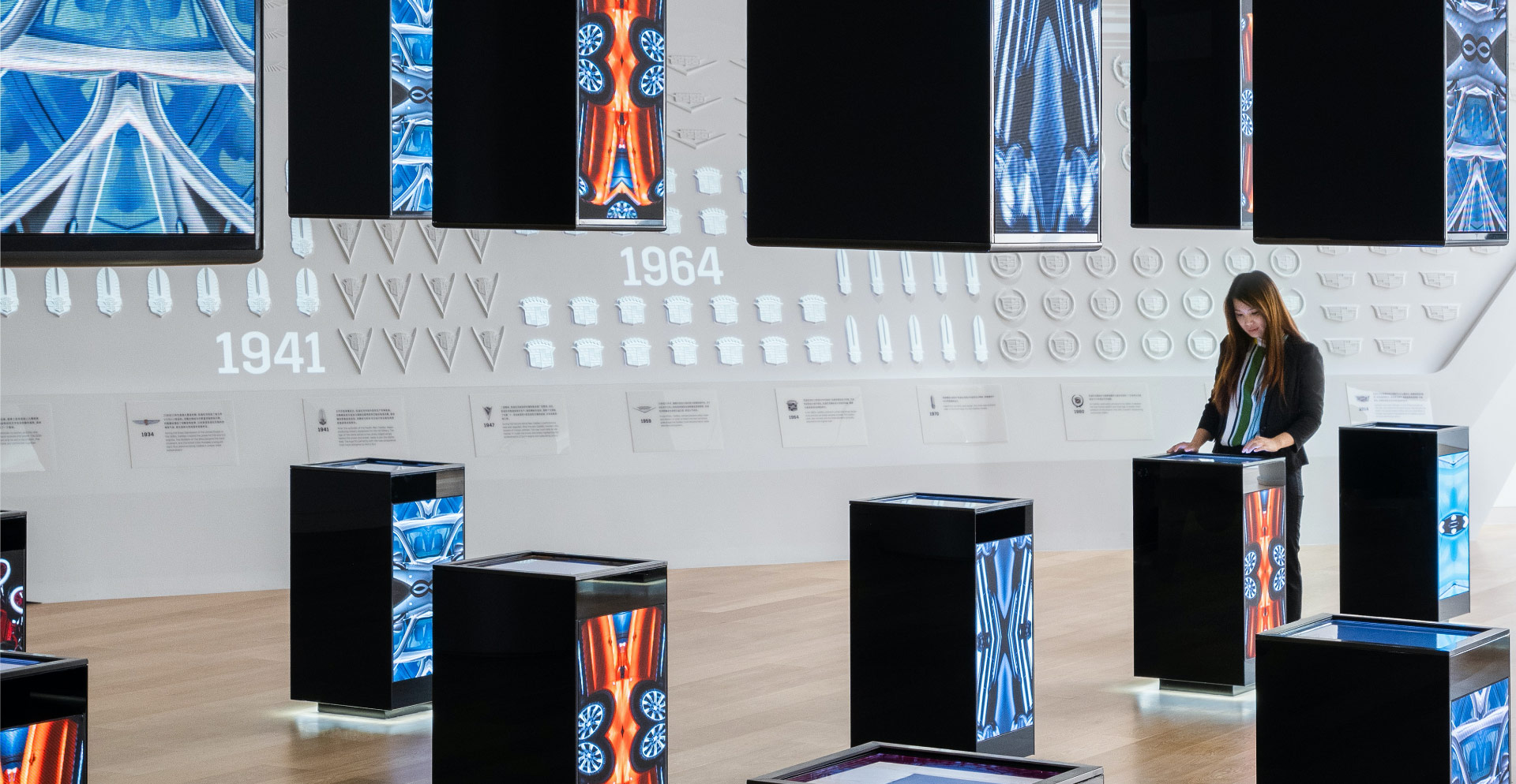 A person standing in front of a wall of computer screens.