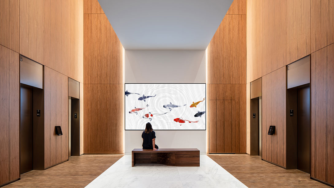 A person sitting on a bench looking at a large screen.