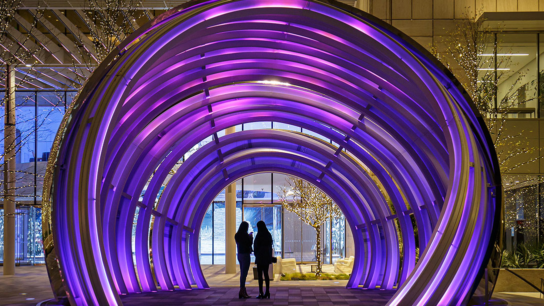 A couple of people walking through a building with a large arched ceiling.