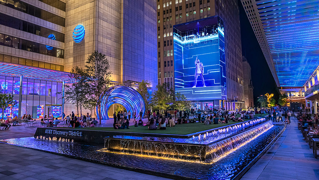 A group of people sitting around a fountain in a city.