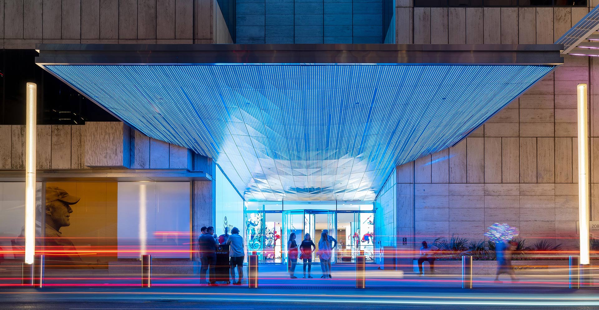 A group of people walking under a building with a large glass roof.