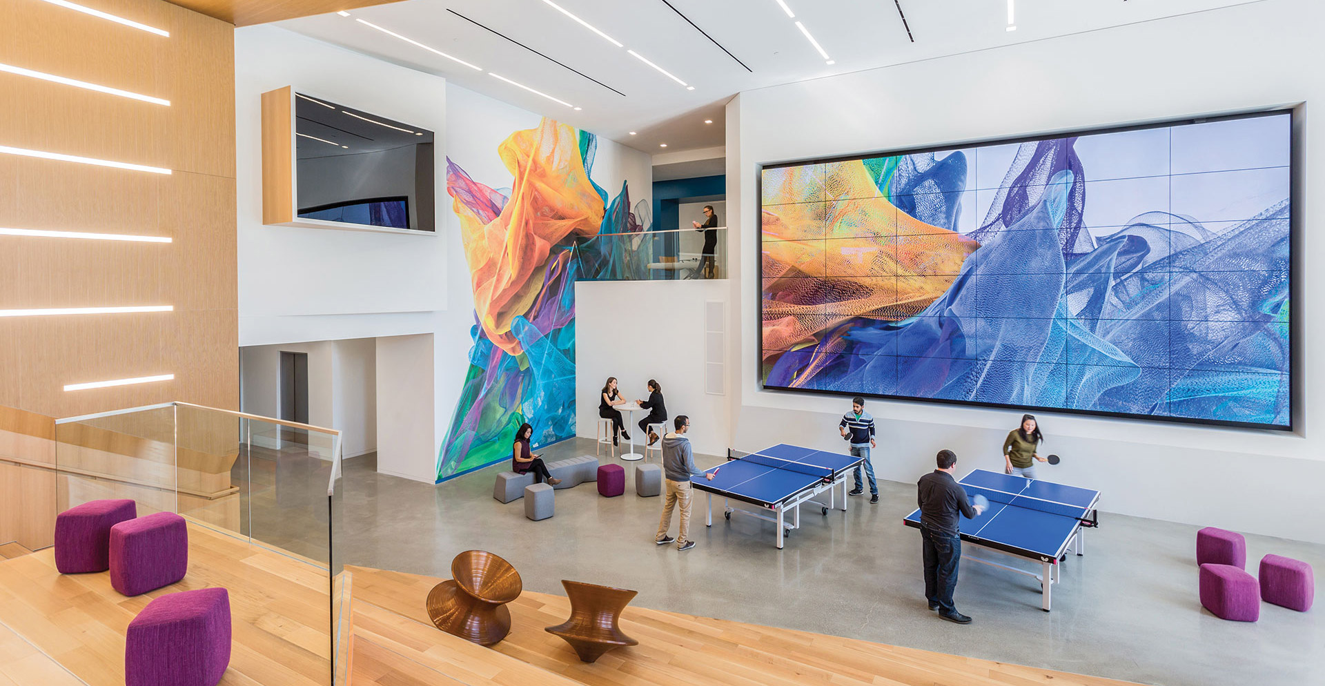 A group of people in a room with large screens.