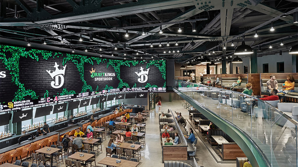 A large sports entertainment venue at DraftKings Sportsbook interior with large screens and a bar