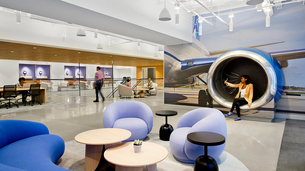 A blue and purple seating area with a plane turbine at United Airlines lounge