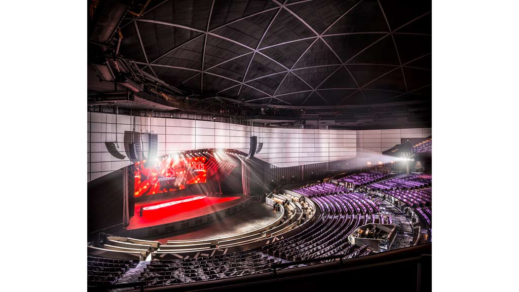 A large room with a stage and a large crowd of people.