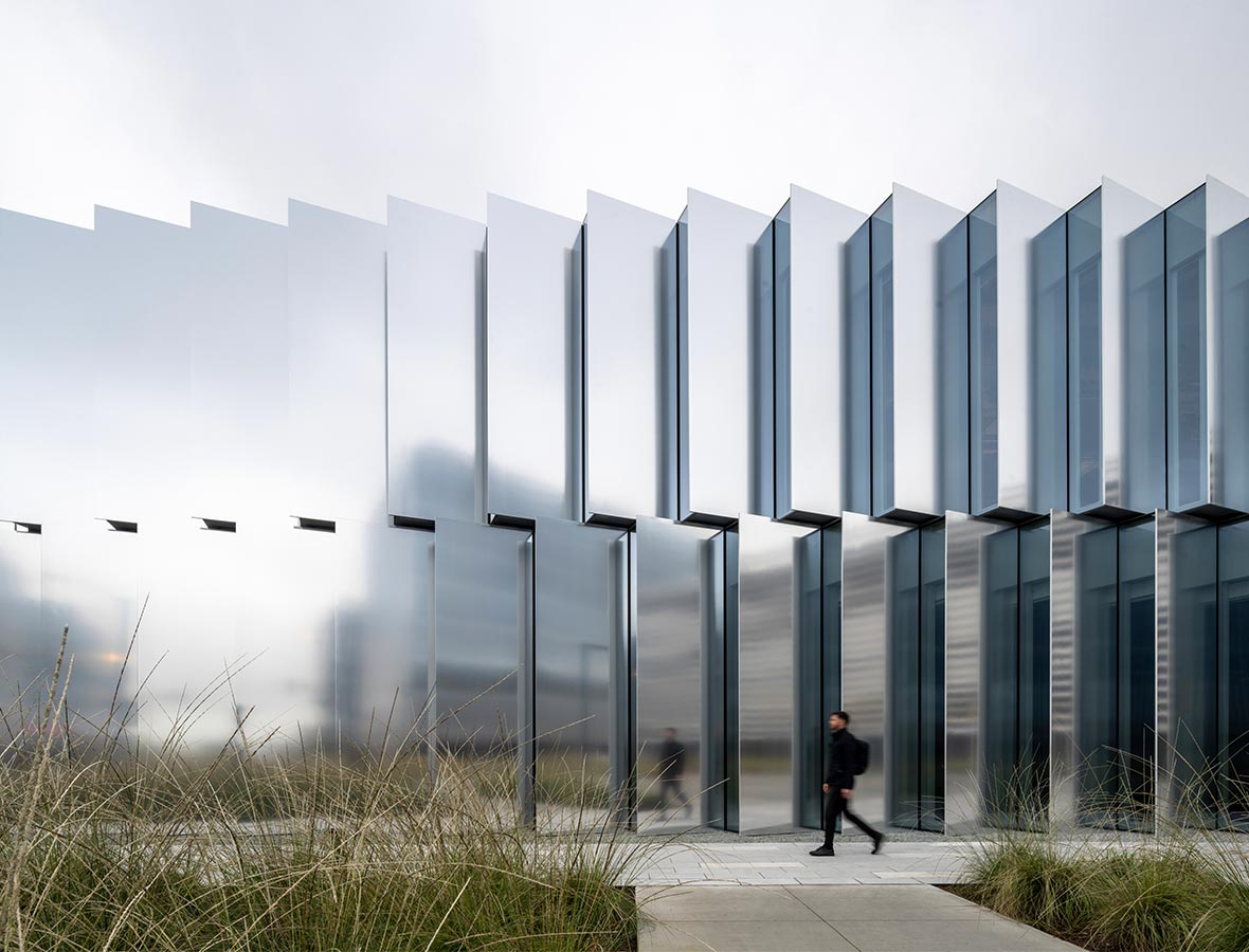 A person walking in front of a large white building.