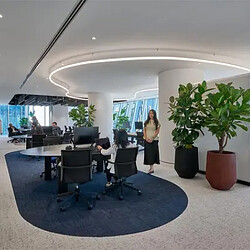 A person standing in a room with a desk and chairs.